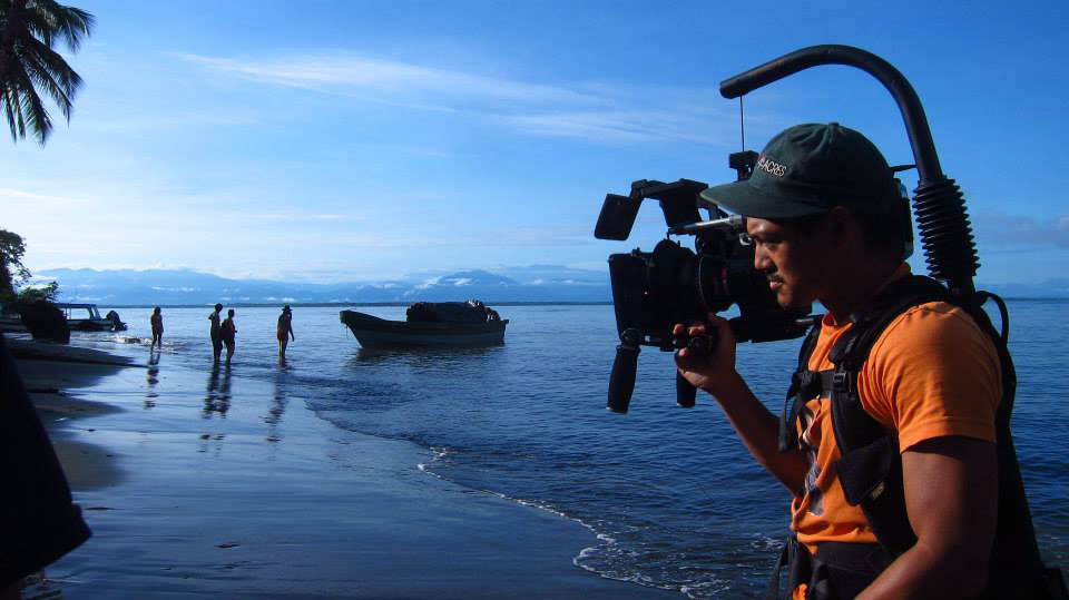 Photo of Alan Blanco operating a video camera on beach