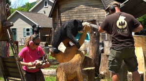 Cedar Mountains Design artists Heath and Hillary Bender carve a bear out of a log with chainsaws