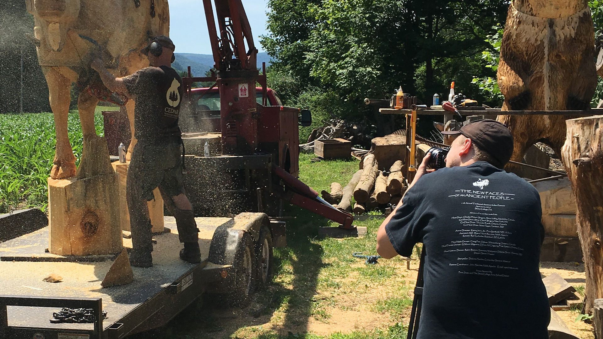 Videographer filming a chainsaw artist carving a cow