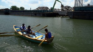 3 young adults row a small boat down a river