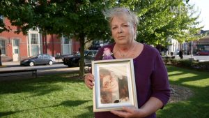 Older woman holding framed photo of young woman