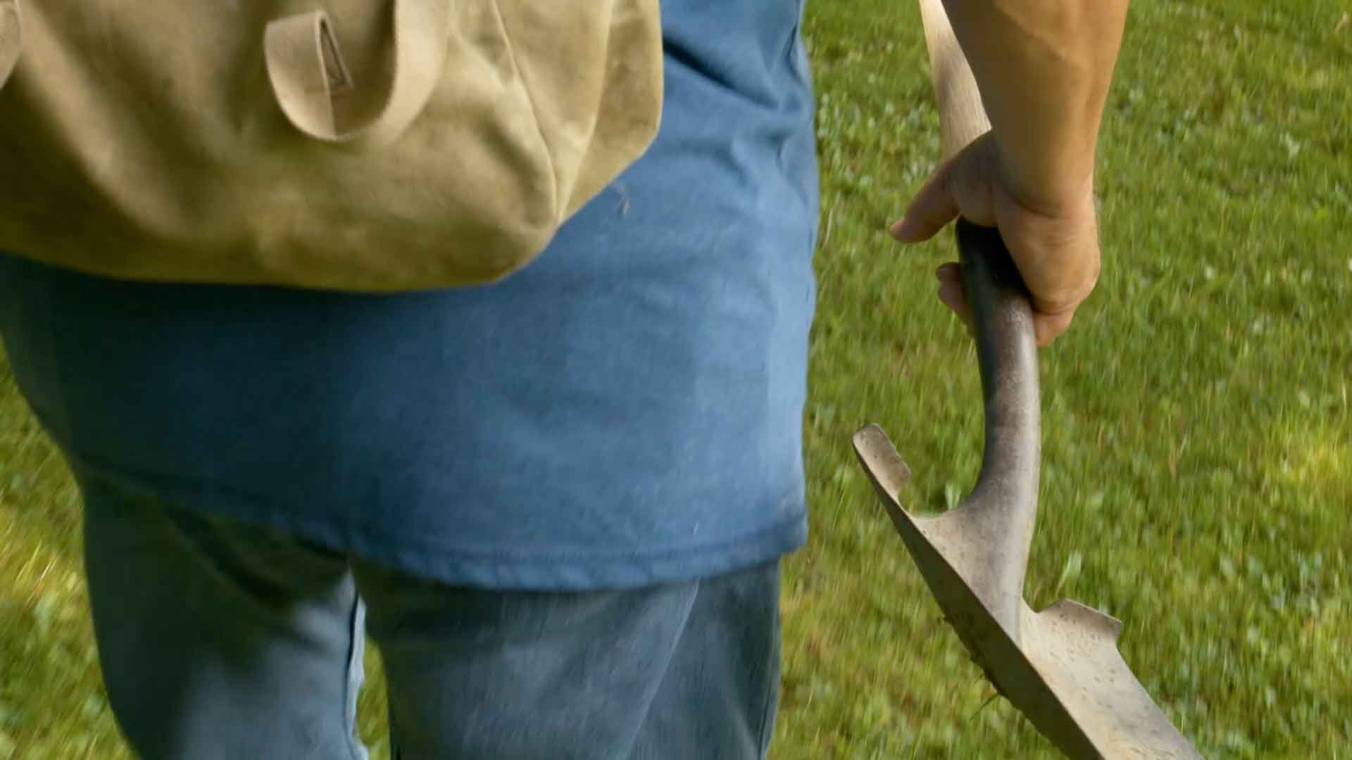 view of man's back holding a shovel in hand