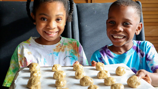 two children in front of a tray of cookie dough