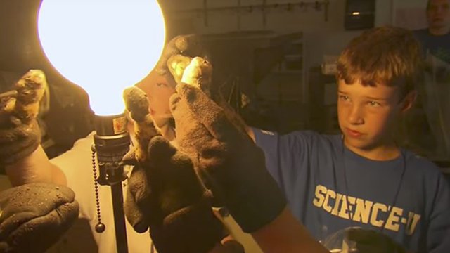 child holding a homemade comet up to a lightbulb