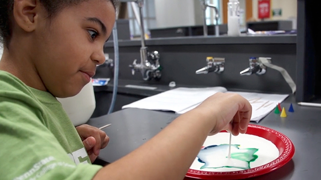 girl mixing colors in a bowl of milk