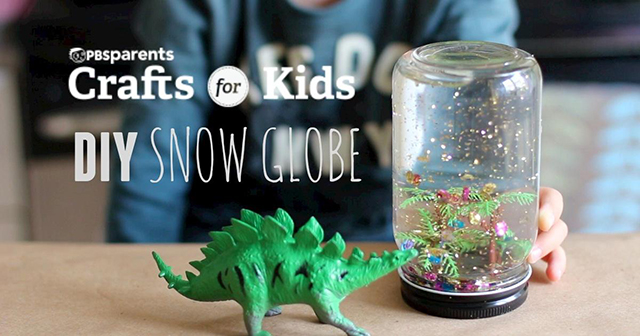 small dinosaur in front of a homemade snow globe
