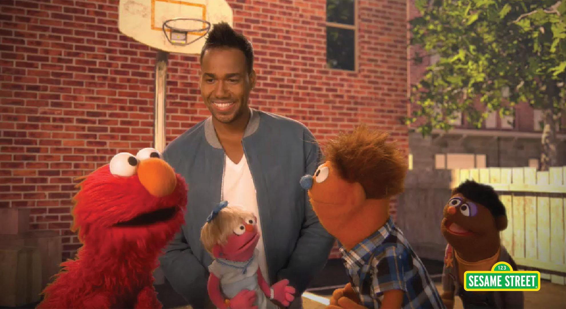 Romeo Santos, a man, standing behind Elmo and other puppets
