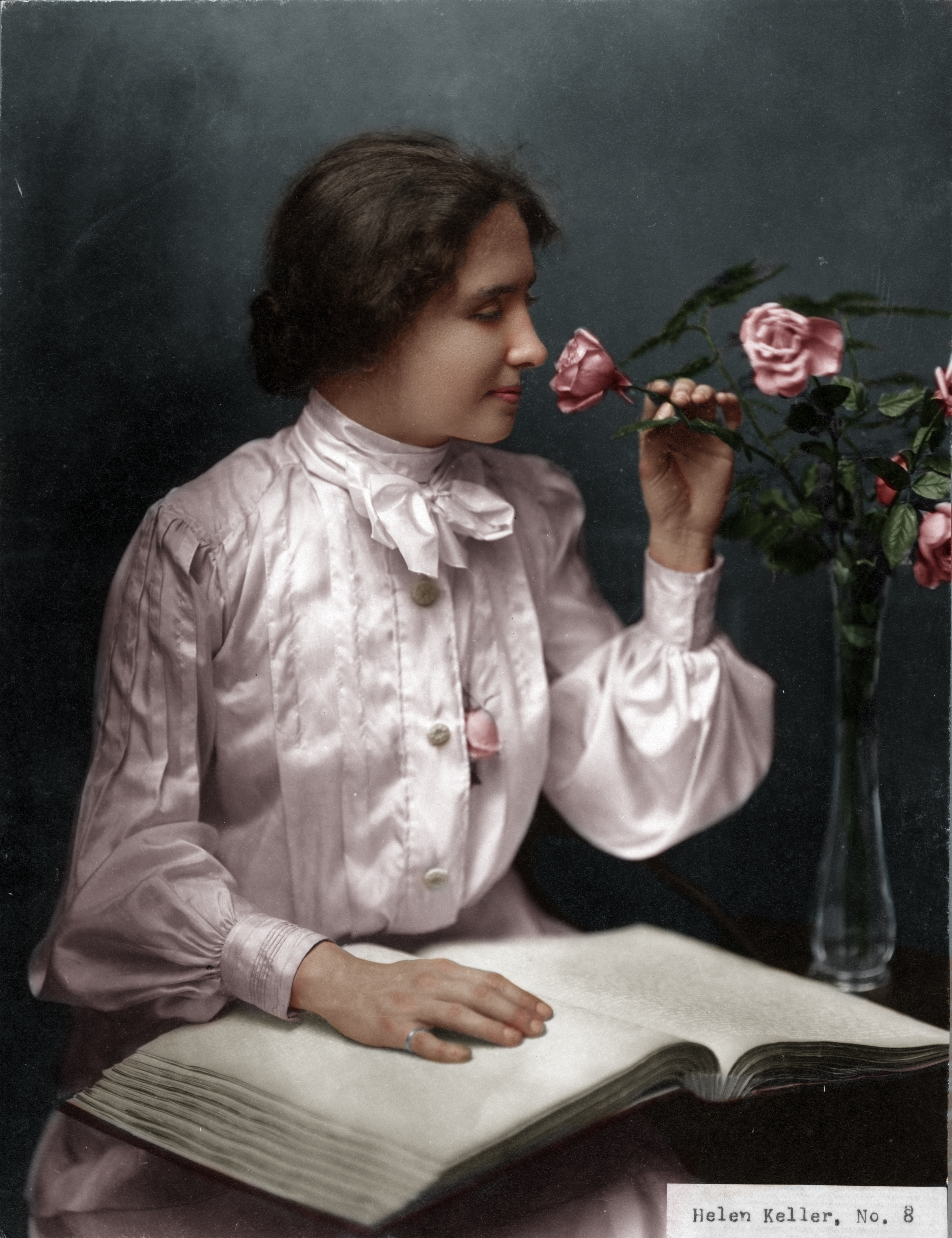 A painting of Helen Keller in a white blouse smelling a pink rose.