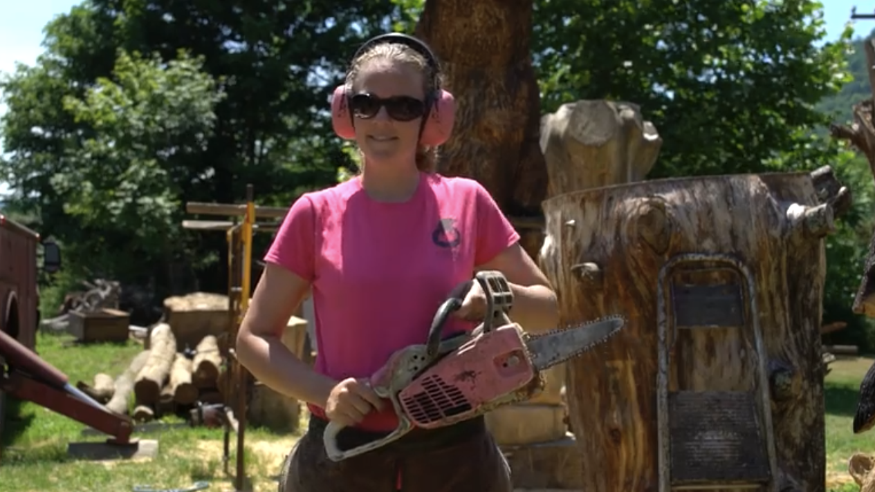A woman in a pink shirt holding a chainsaw