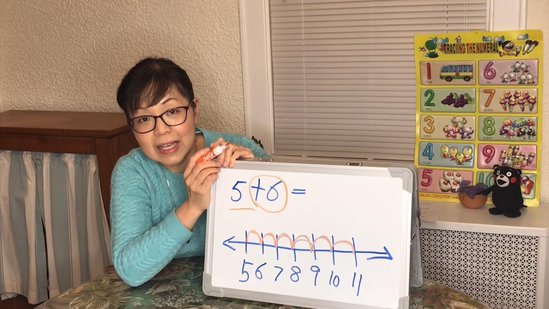 A woman holding a whiteboard with a number line drawn on it