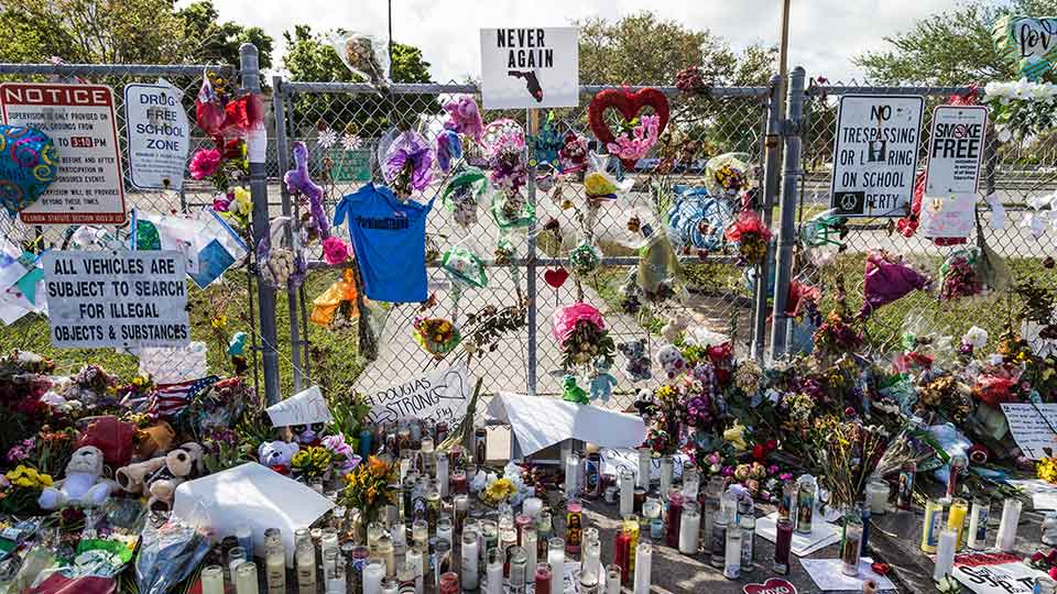 memorial of flowers and candles at a school gate