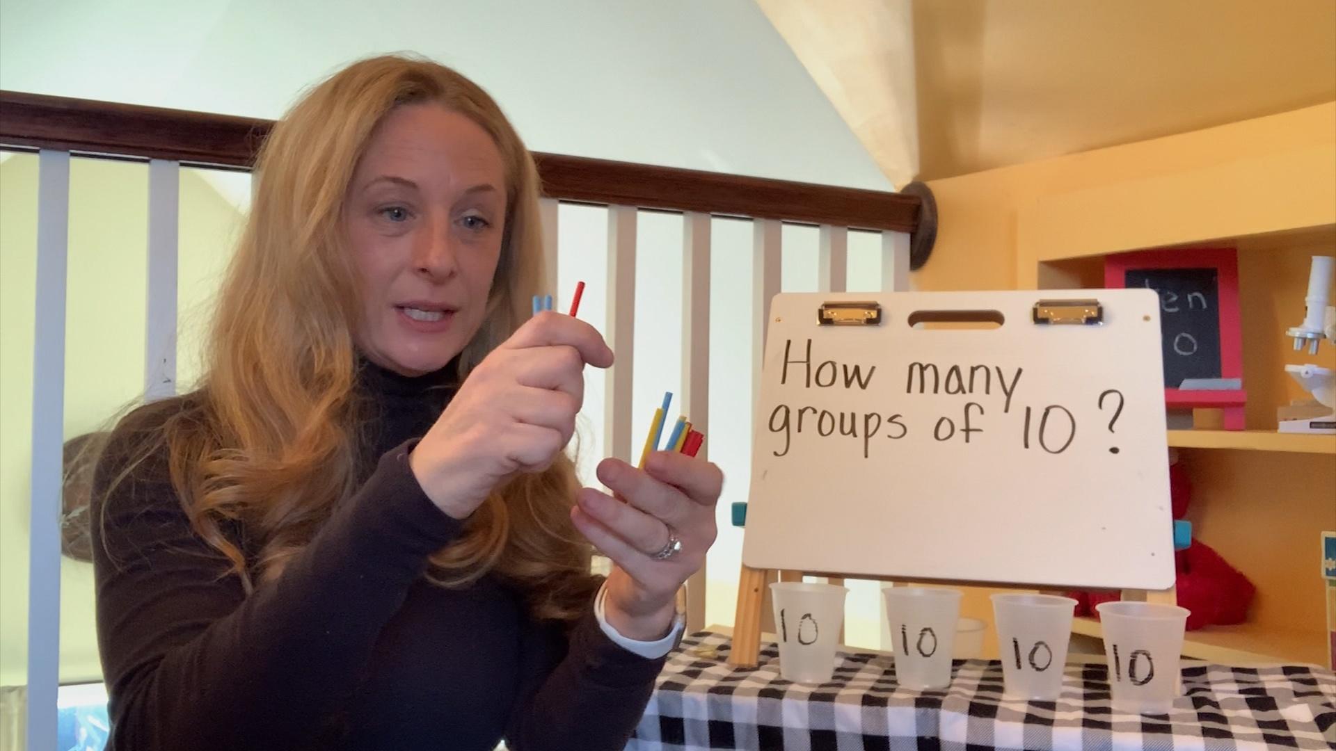 A woman demonstrating counting in front of a whiteboard