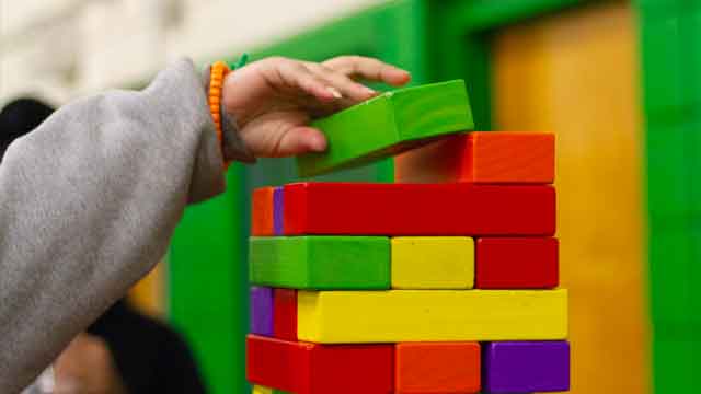 child's hand stacking colorful blocks