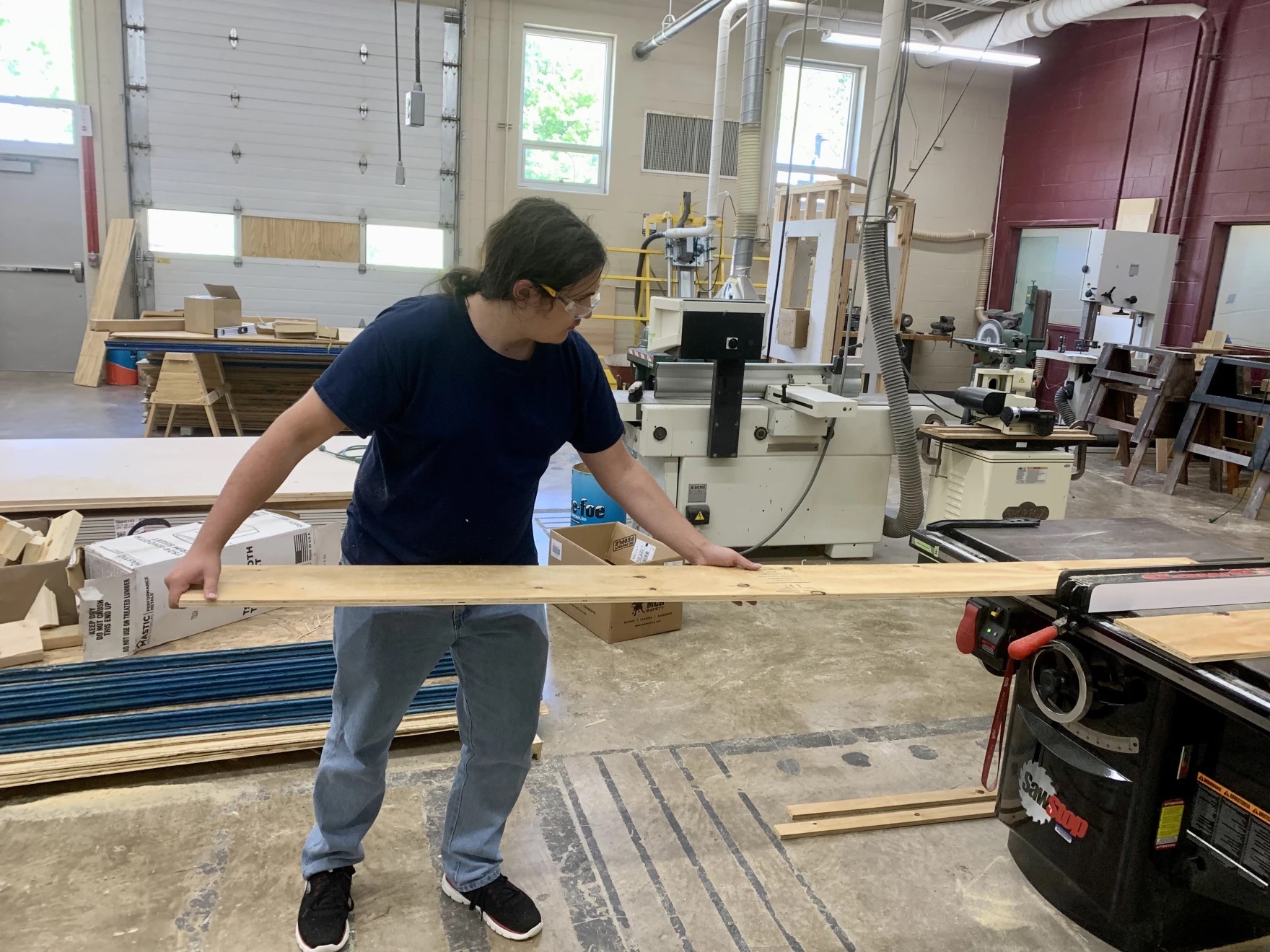 A student putting a board through a saw