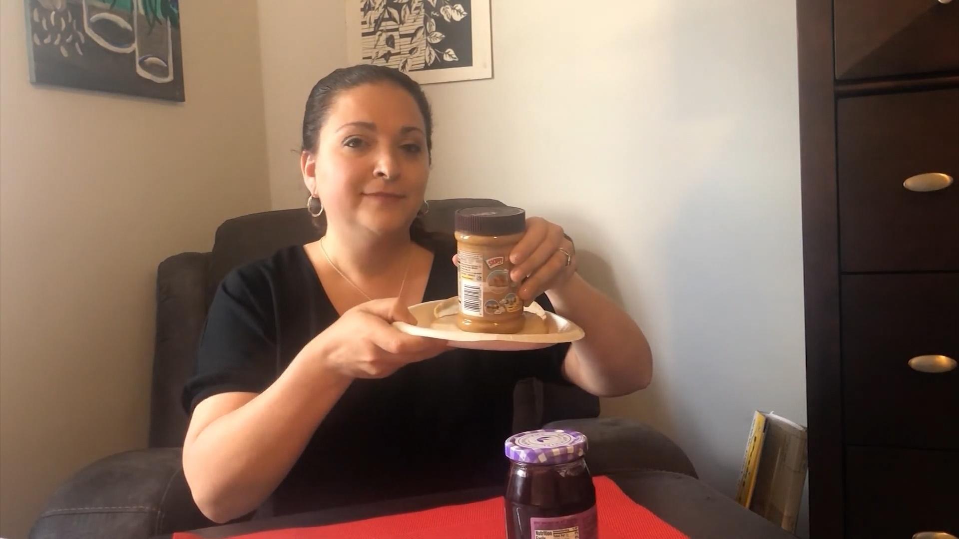 A woman holding a jar of peanut butter on a plate.