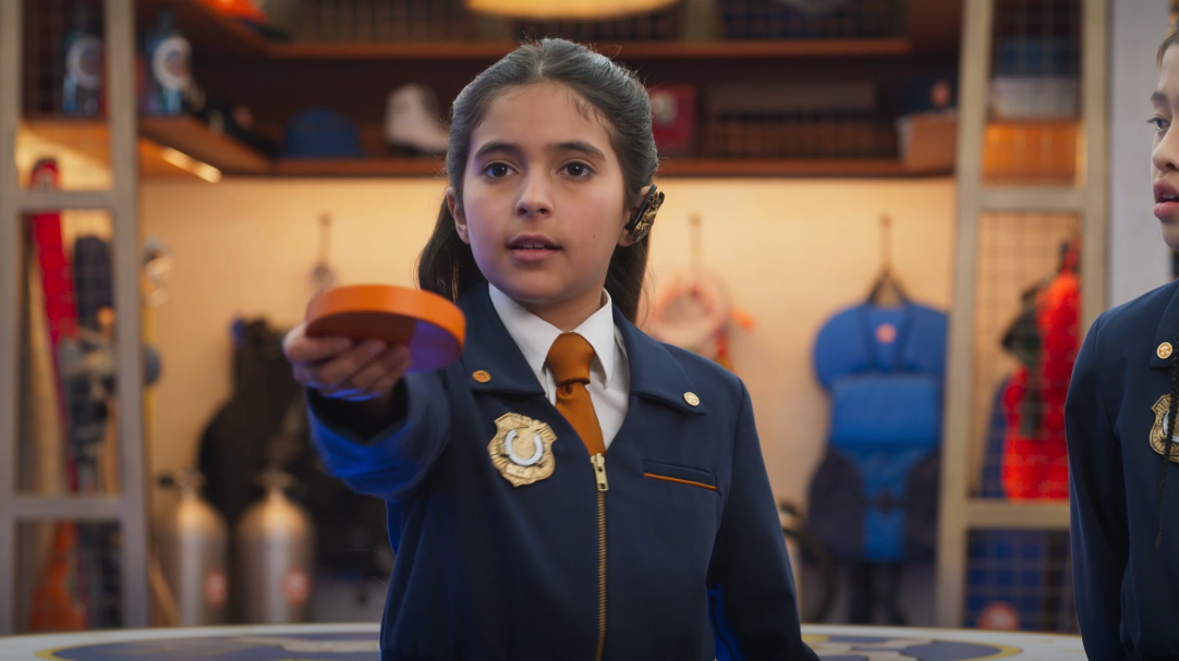 A girl holding out an orange puck.