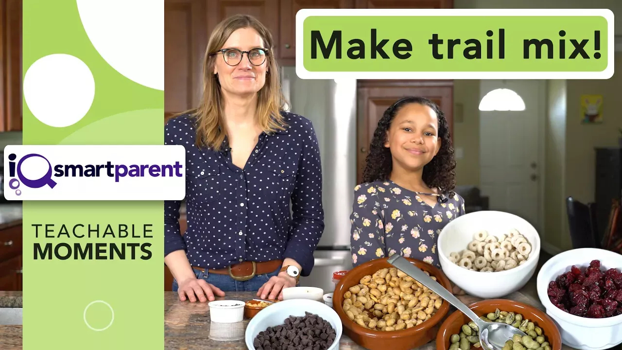 A woman and a girl standing in front of bowls to make a trail mix snack.