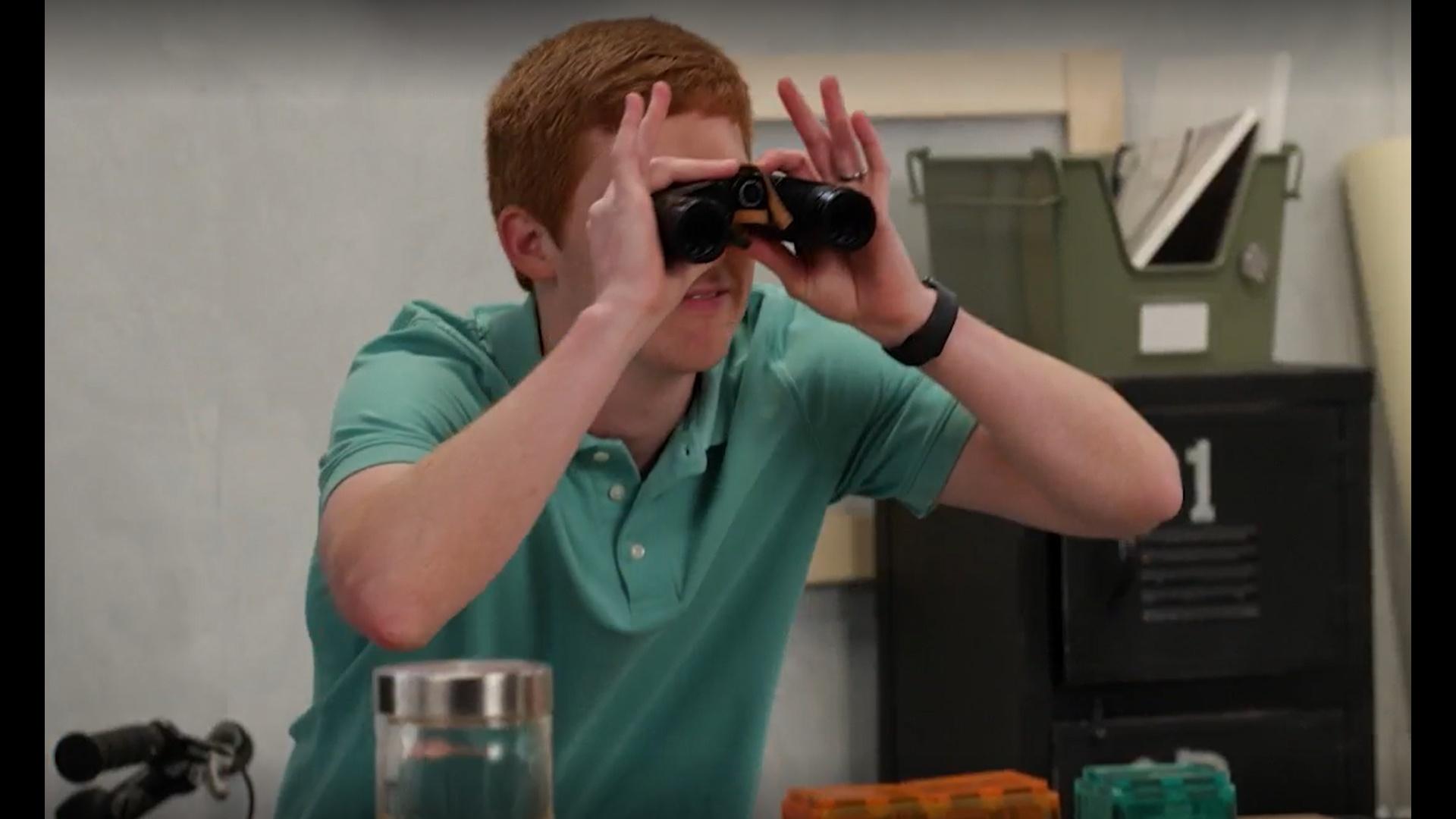 A man looks through binoculars.