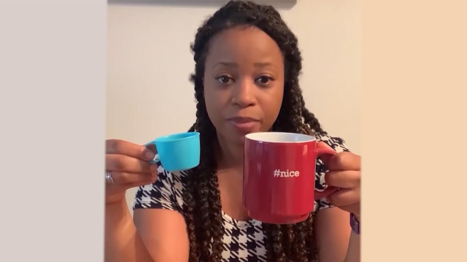 A woman holds up two different sized cups to the camera.