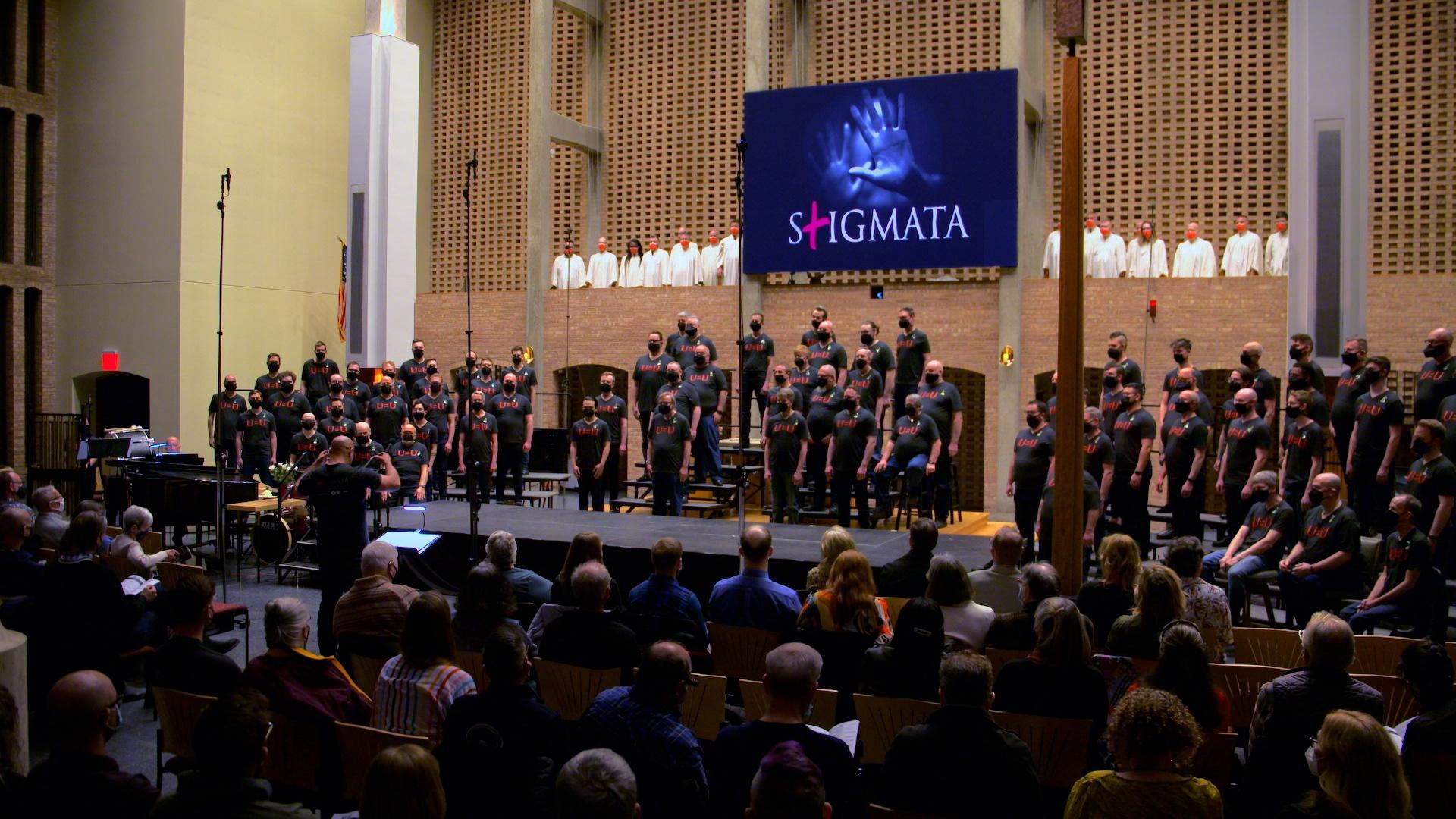 A choir sings on a stage in front of an audience.