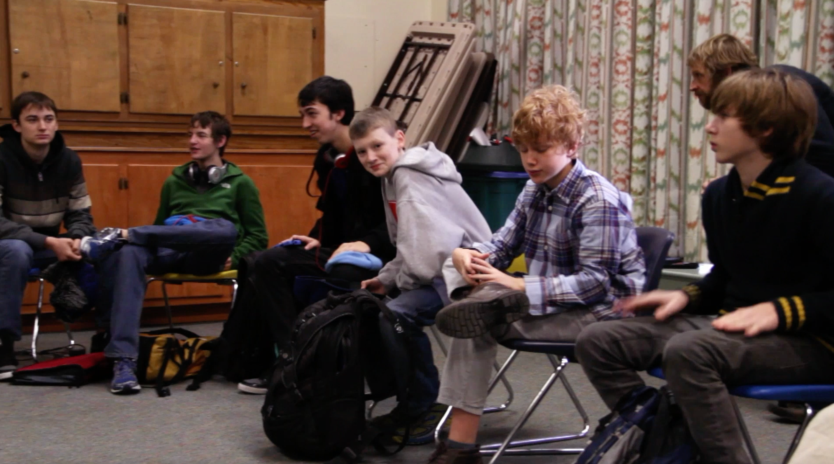 A group of boys sit next to each other in a circle.