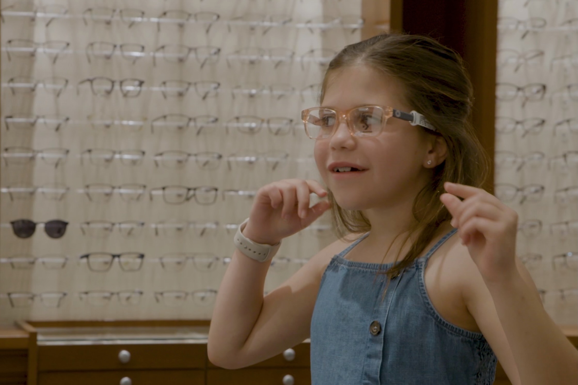 A young girl trying on glasses in an eye doctor's office.