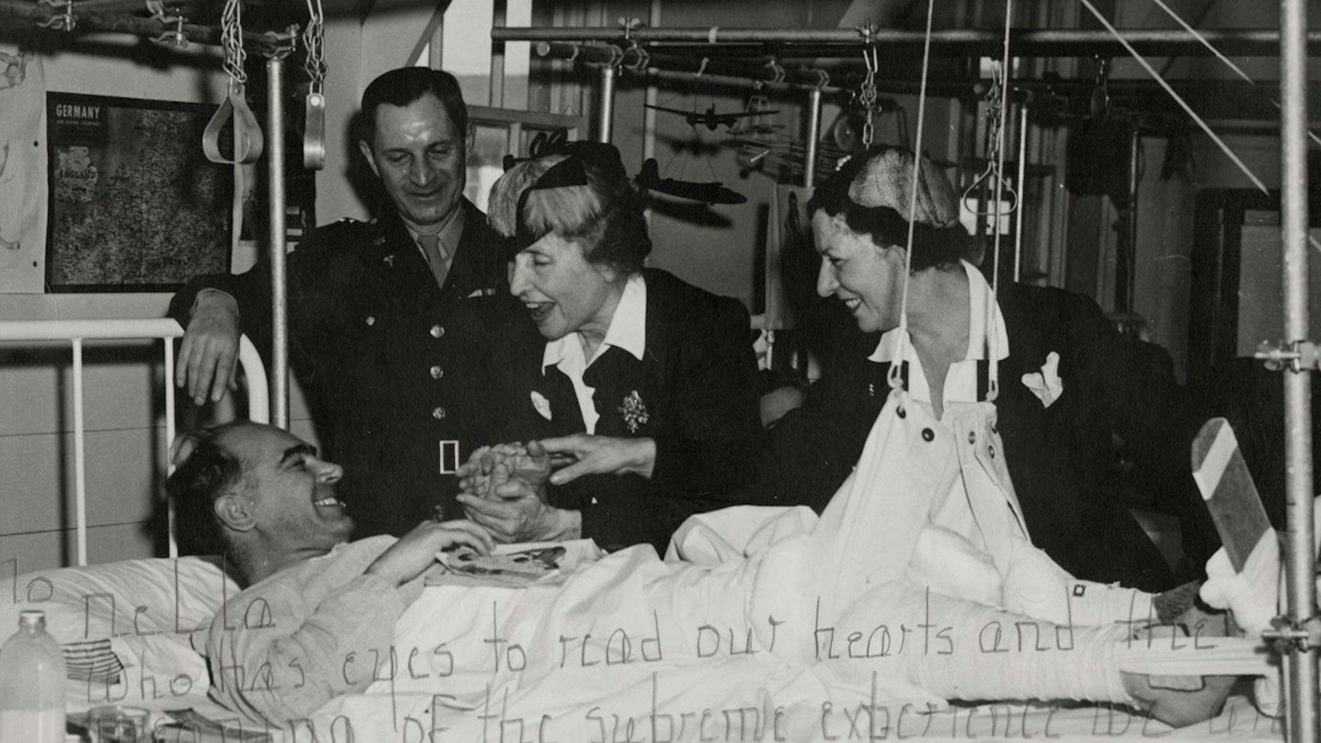 A black-and-white image of two women and a man meeting with a second man lying in a hospital bed.