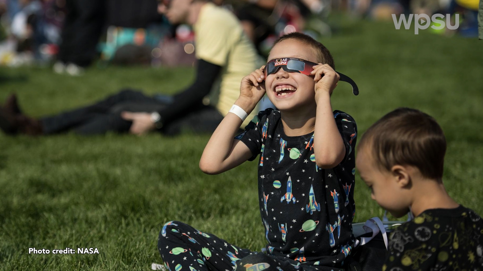 A child watching a solar eclipse while wearing safety glasses.