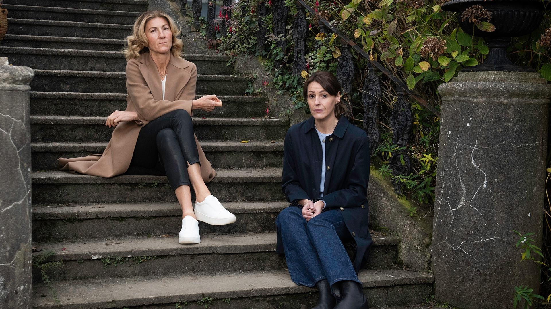 Two female actors sitting on stone steps.