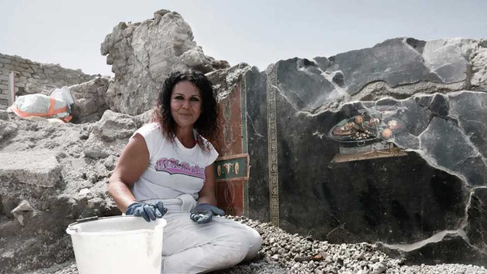 Woman sitting in front of ancient wall.