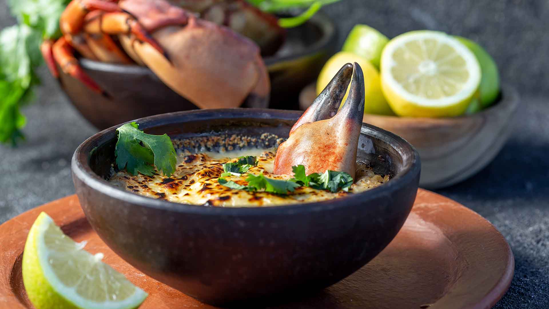 black bowl filled with a cream soup with a crab claw.