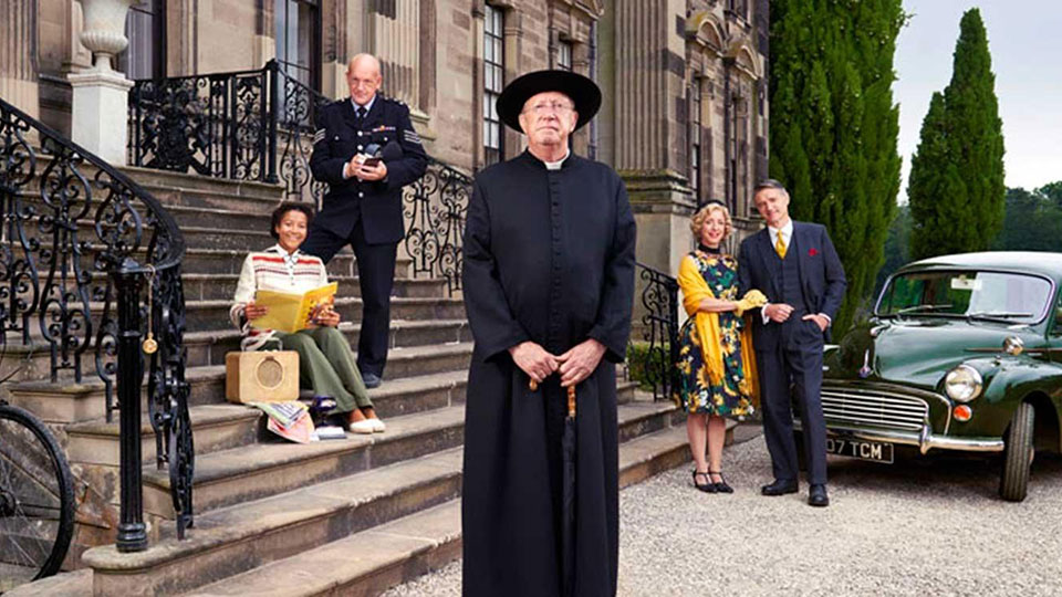 Cast of Father Brown sitting on the steps of an old building.