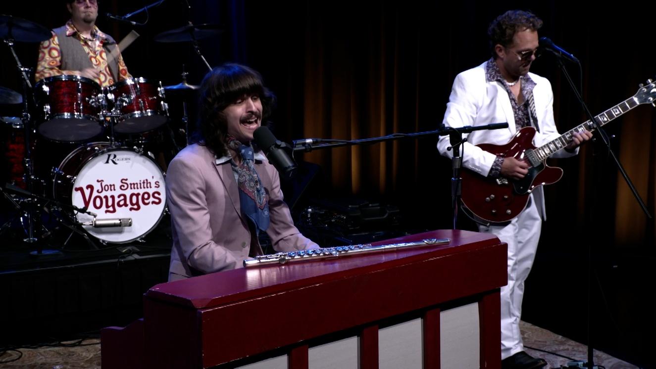 Band members in vintage attire performing on piano, guitar, and drums.