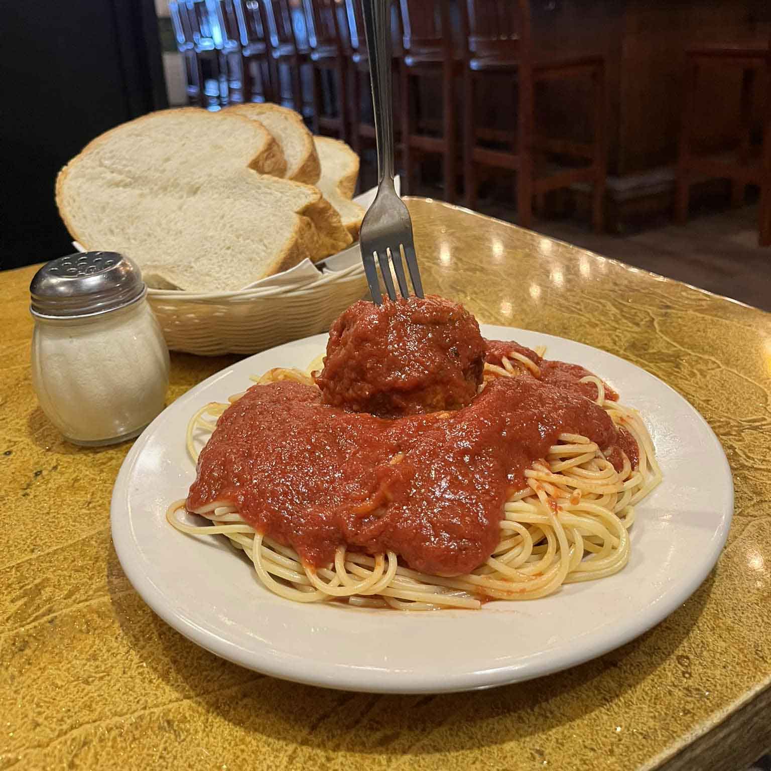 spaghetti topped with tomato sauce and a large meatball