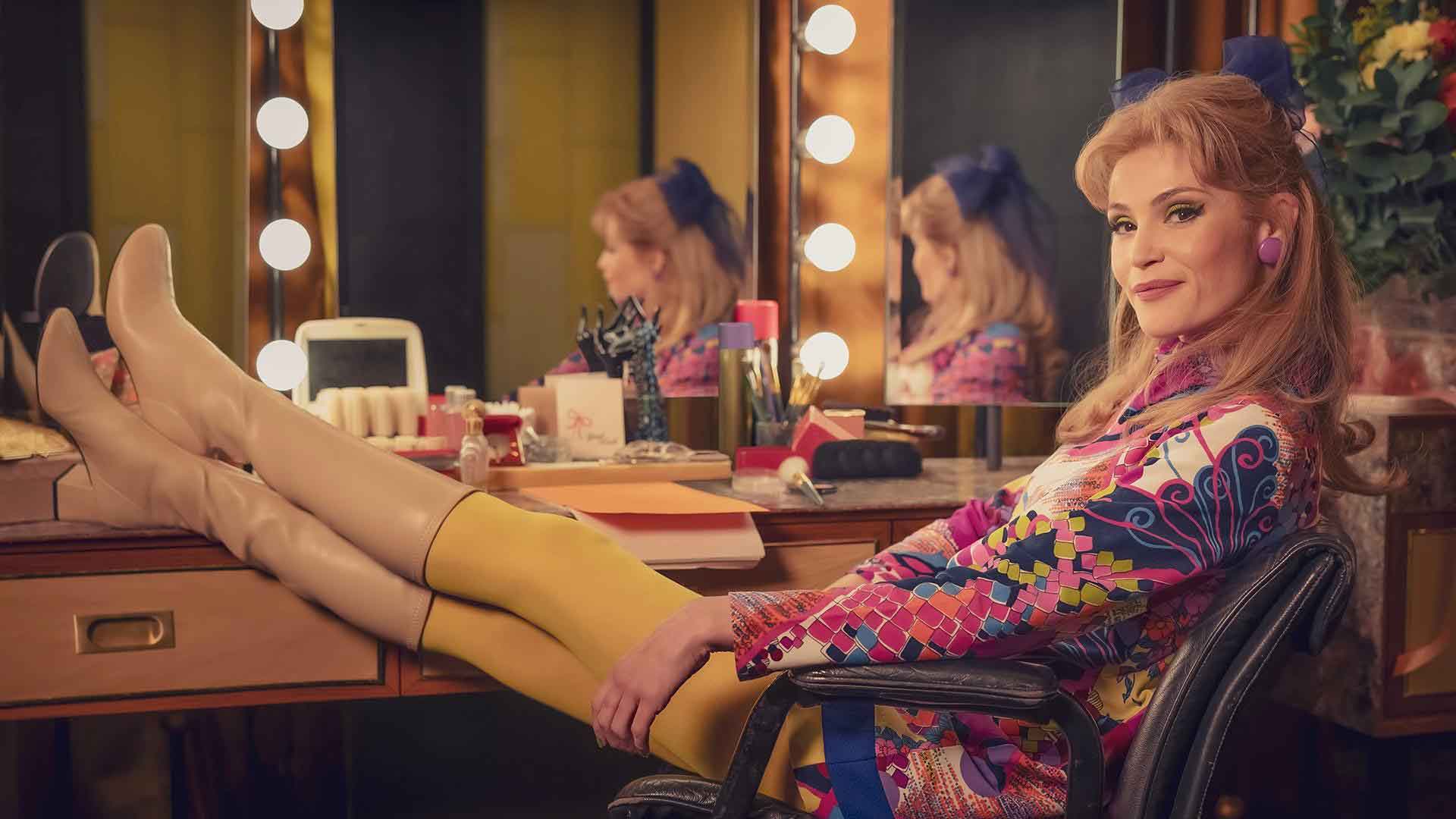 Funny Woman actress sitting with feet up on dresser.