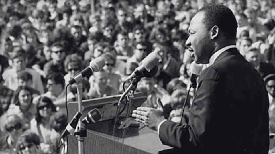 Martin Luther King Jr addressing a large crowd.