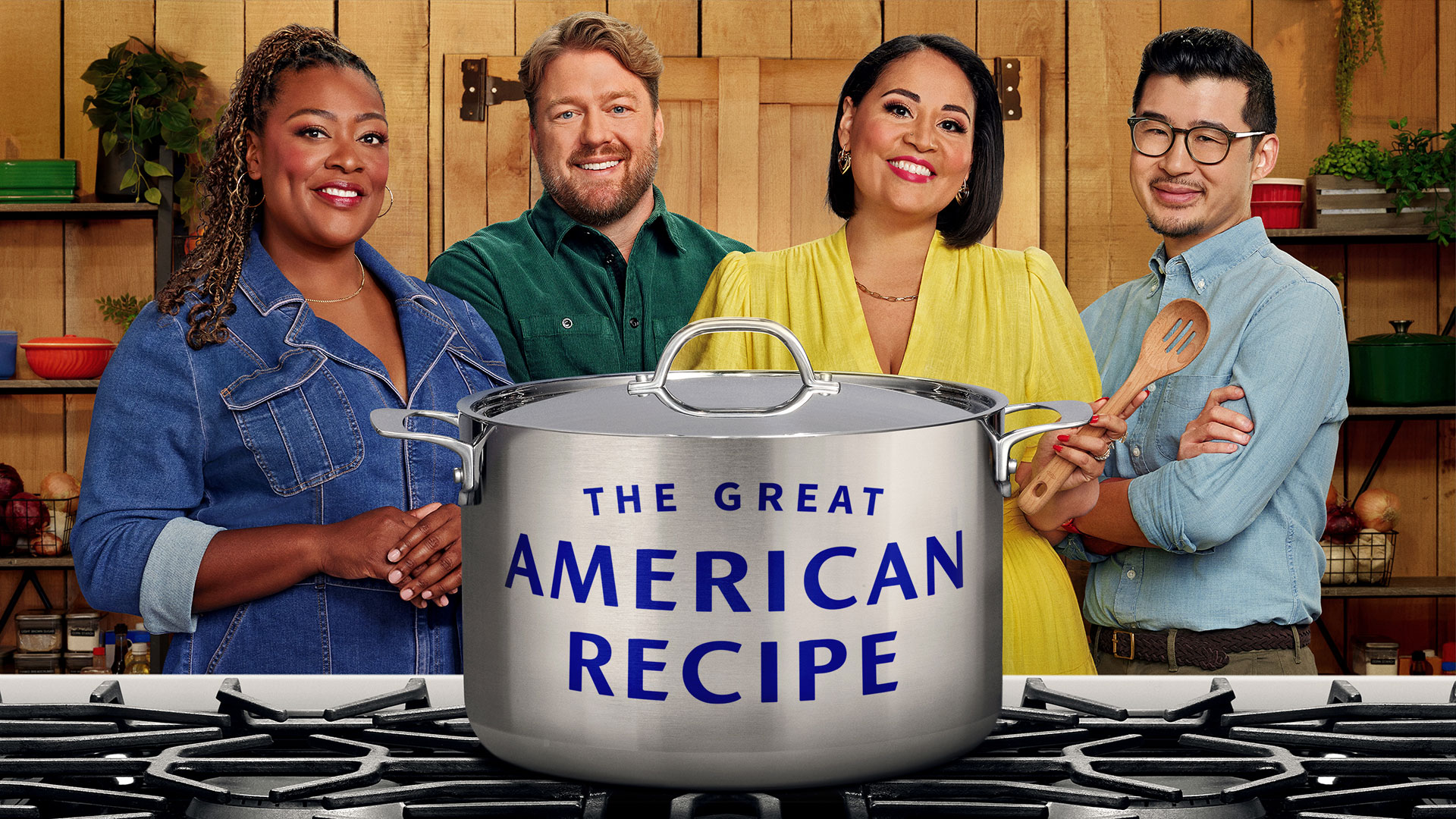 Two men and two women standing behind a large cooking pot.